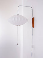 Unlit saucer-shaped shade on this Clérachic wall light, with its pull cord, white cable and in-line switch against a pale wall corner.