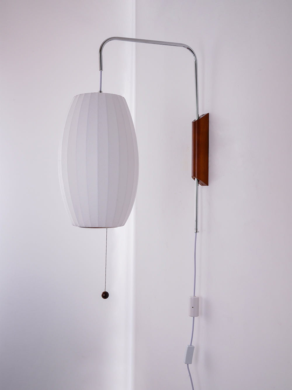 Same oval shade of this Clérachic wall light switched off, showing a soft grey-white fabric look against the pale wall.