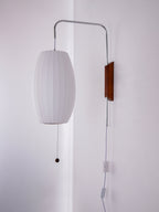 Same oval shade of this Clérachic wall light switched off, showing a soft grey-white fabric look against the pale wall.