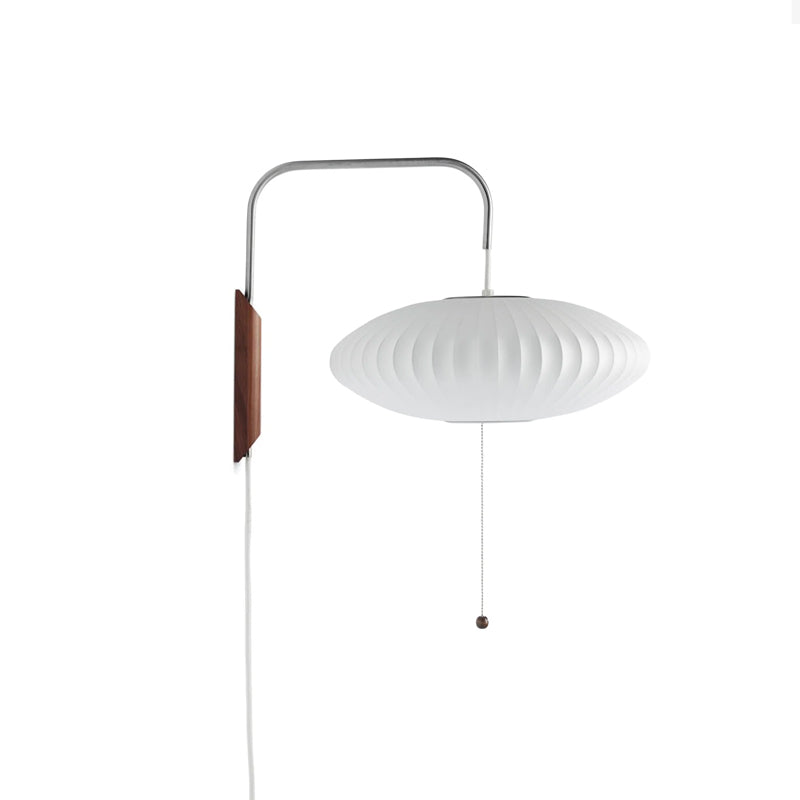 A flat saucer-shaped white shade hangs from a Clérachic wall arm with a walnut bracket and bead pull on a plain white backdrop.