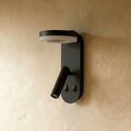 Clérachic matte black wall reading light unlit on limewash, showing its flat ring panel, tube spotlight and two switches.