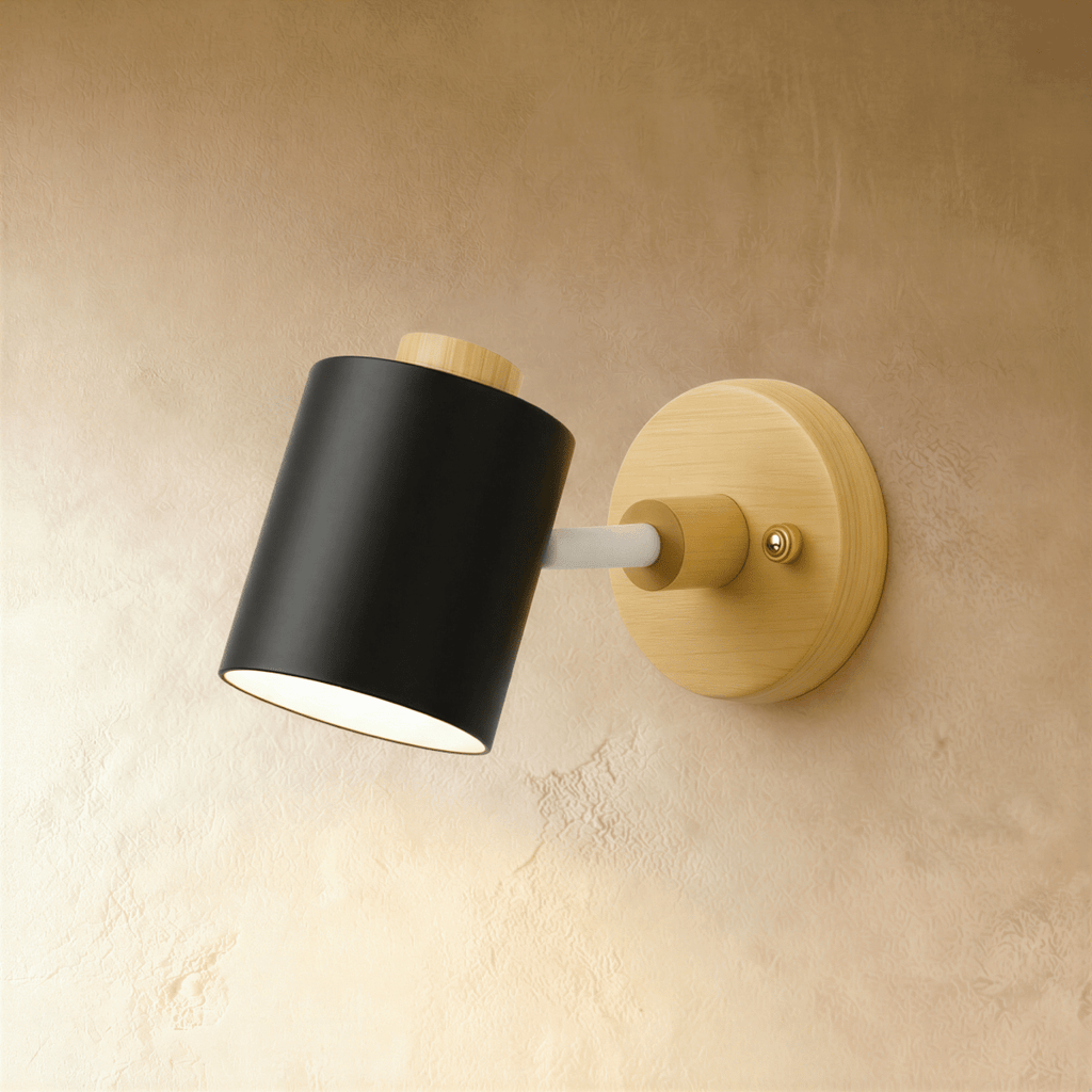 Clérachic wall lamp with a matte black cylindrical metal shade and white arm on a light wood backplate, on a limewash wall.