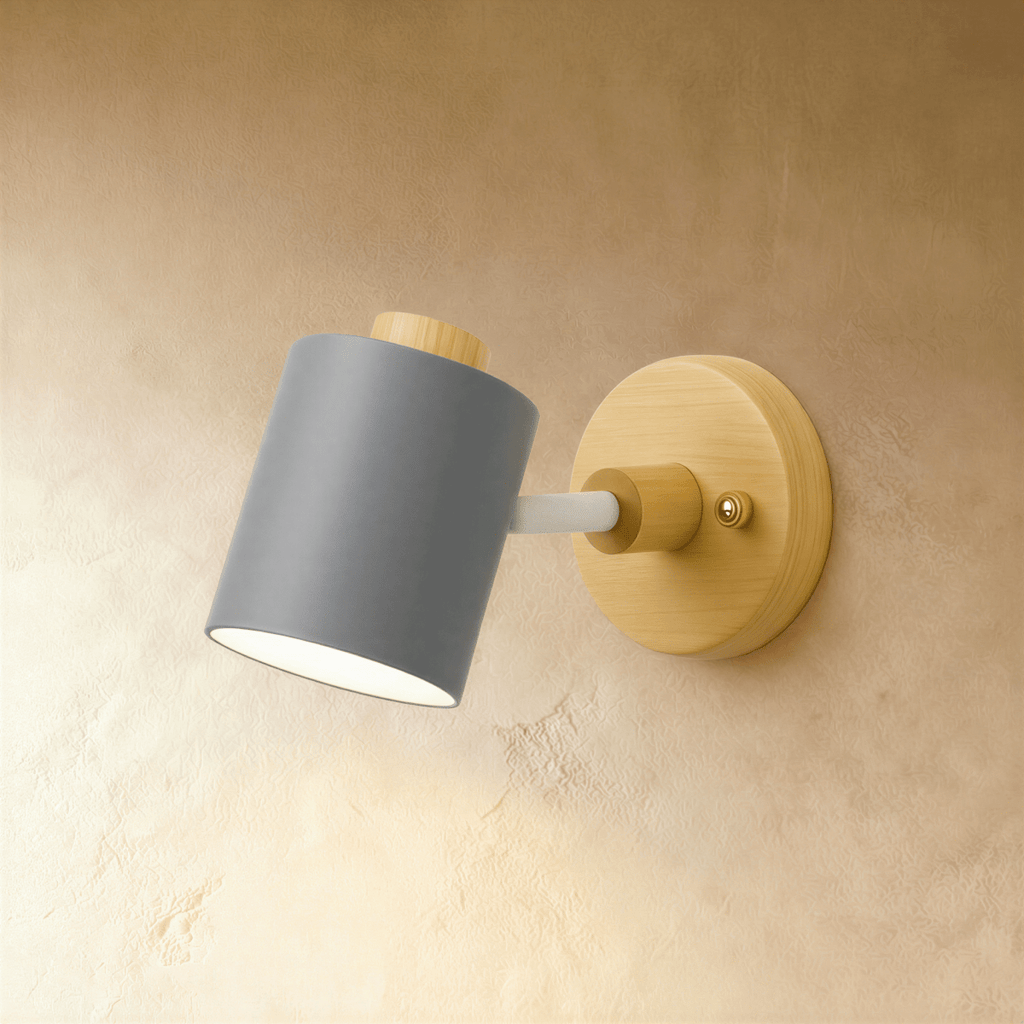 Clérachic wall lamp with a slate grey cylindrical metal shade on a pale wood round backplate, angled on a limewash wall.