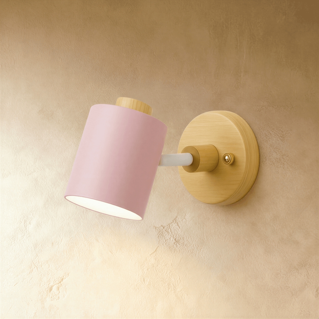 Clérachic wall lamp with a soft pink cylindrical metal shade and white arm on a light wooden backplate, on a limewash wall.