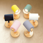 Clérachic wall lamp range in six shade colours on round wooden bases, with GU10 bulbs glowing inside the open shades.