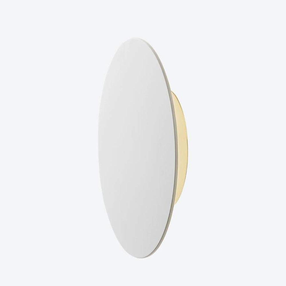 Side view of a white Clérachic disk wall light on a pale backdrop, with a brass back plate showing behind it.