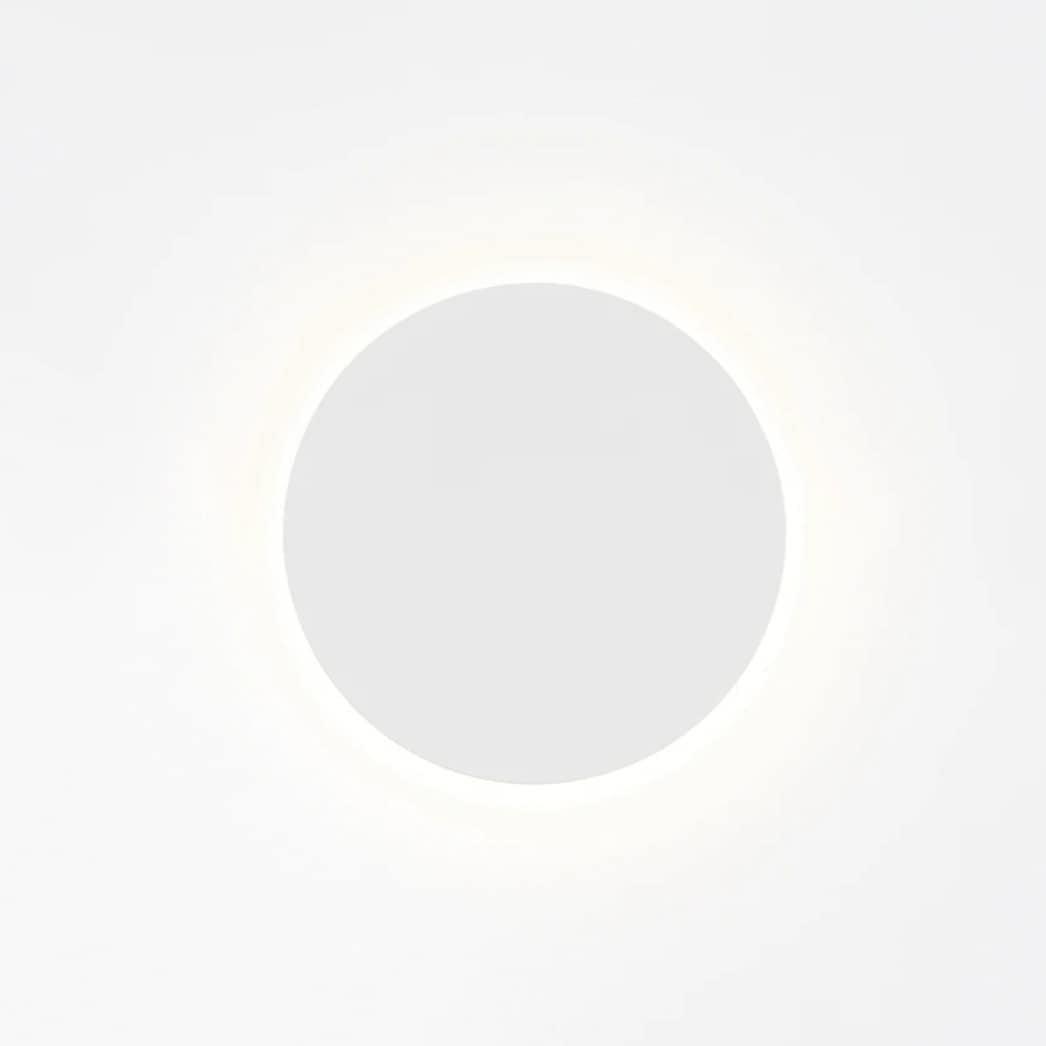White round Clérachic wall light on a bright backdrop, with a faint glow circling the disk.
