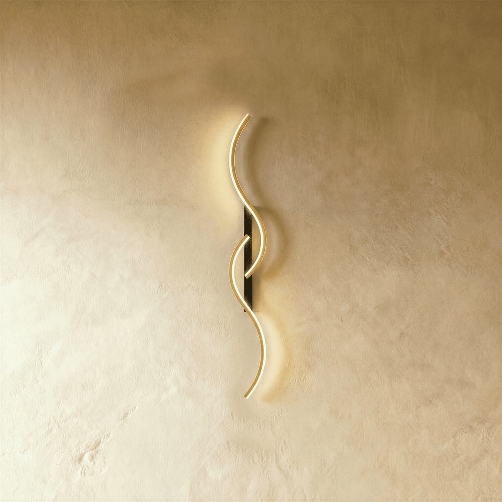 Clérachic S-shaped wall light with two interlocking gold LED curves on a slim black backplate, glowing against warm limewashed plaster.