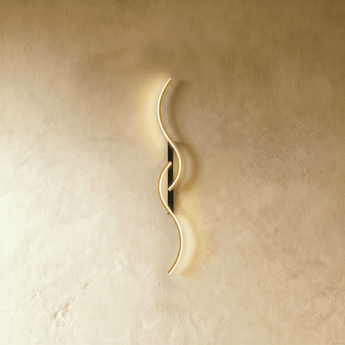 Clérachic S-shaped wall light with two interlocking gold LED curves on a slim black backplate, glowing against warm limewashed plaster.