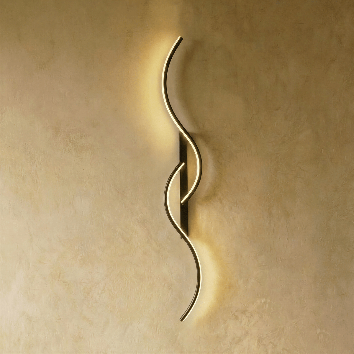 Clérachic tall black S-shaped wall light with two overlapping LED curves, casting a gentle warm glow down a plaster wall.