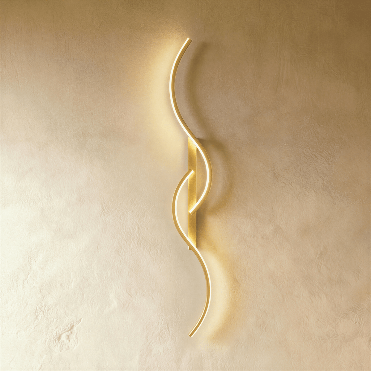 Clérachic tall gold S-shaped wall light with two overlapping LED curves on a gold backplate, glowing against pale plaster.