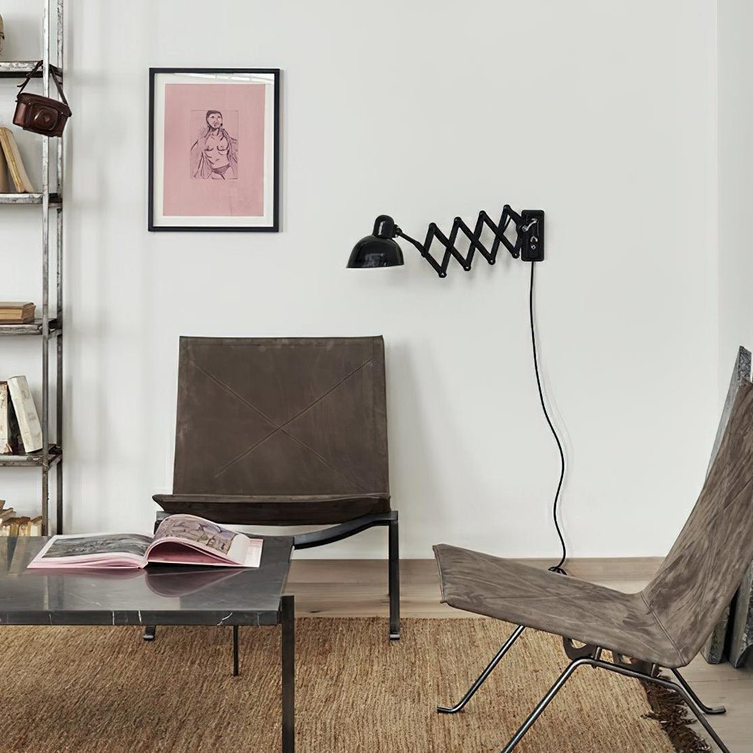 Black Clérachic scissor-arm wall light above a living area with a leather chair and an open book on a low table.