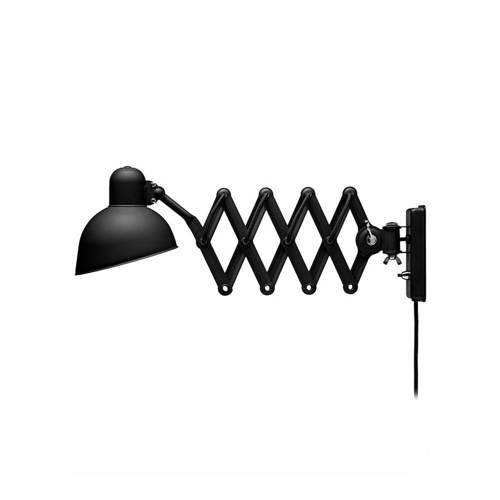 Black Clérachic scissor-arm wall light with the arm stretched out and the shade tilted down, on a white backdrop.