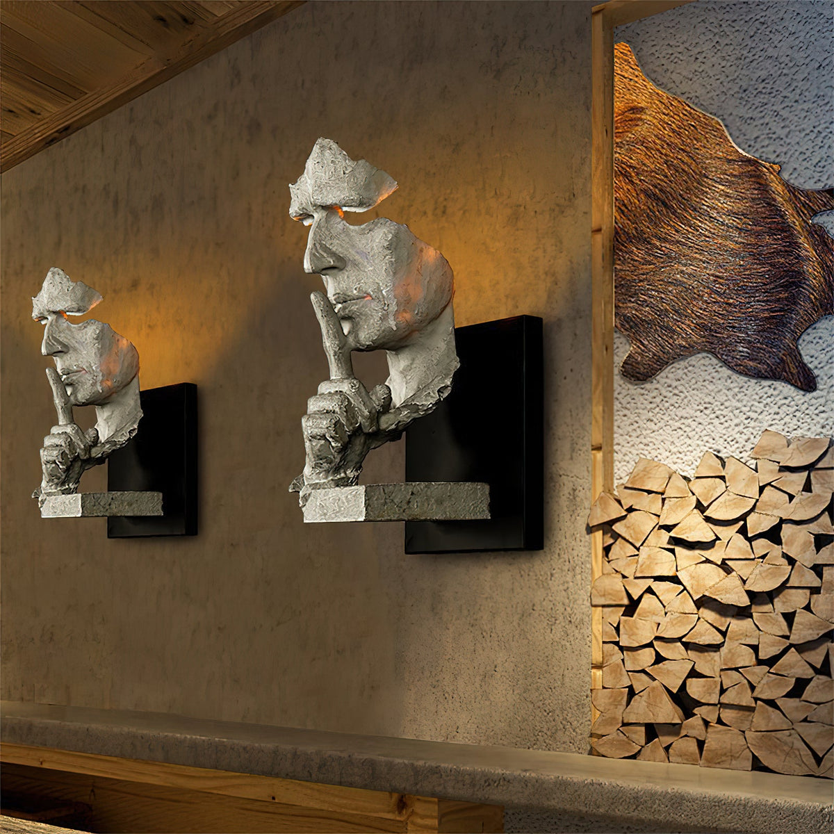 Two white Clérachic face wall lights glowing on a rough plaster wall, beside a stack of split logs and a fur hide.