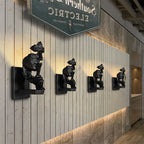 Four black Clérachic face wall lights set in a line along a pale wooden-panelled wall, each casting a glow upward.