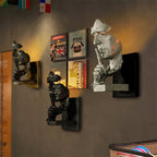 Several Clérachic face wall lights in black and white grouped on a dark wall near framed posters.