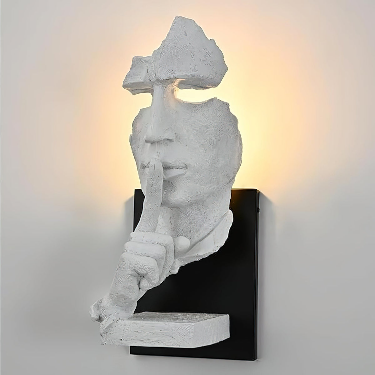 Close view of the white Clérachic wall light on a pale grey wall, showing the face, the finger at the lips and the black mounting plate.
