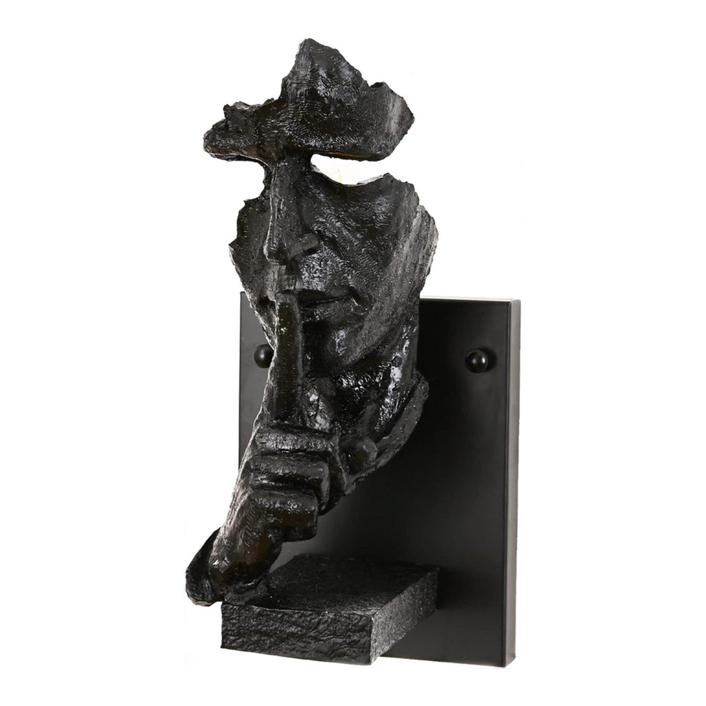 Black Clérachic face wall light photographed on white, showing the rough dark resin surface and the small shelf under the hand.