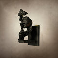 Side profile of a black Clérachic face wall light with specks of rust-orange, on a mottled beige backdrop.