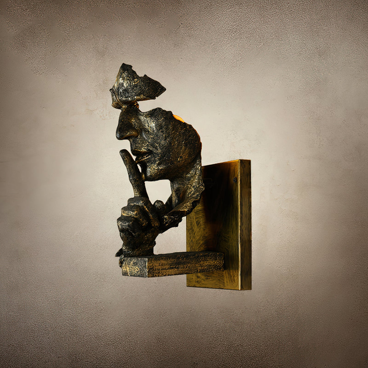 Side profile of a bronze Clérachic face wall light with a worn gold-toned plate, on a mottled beige backdrop.