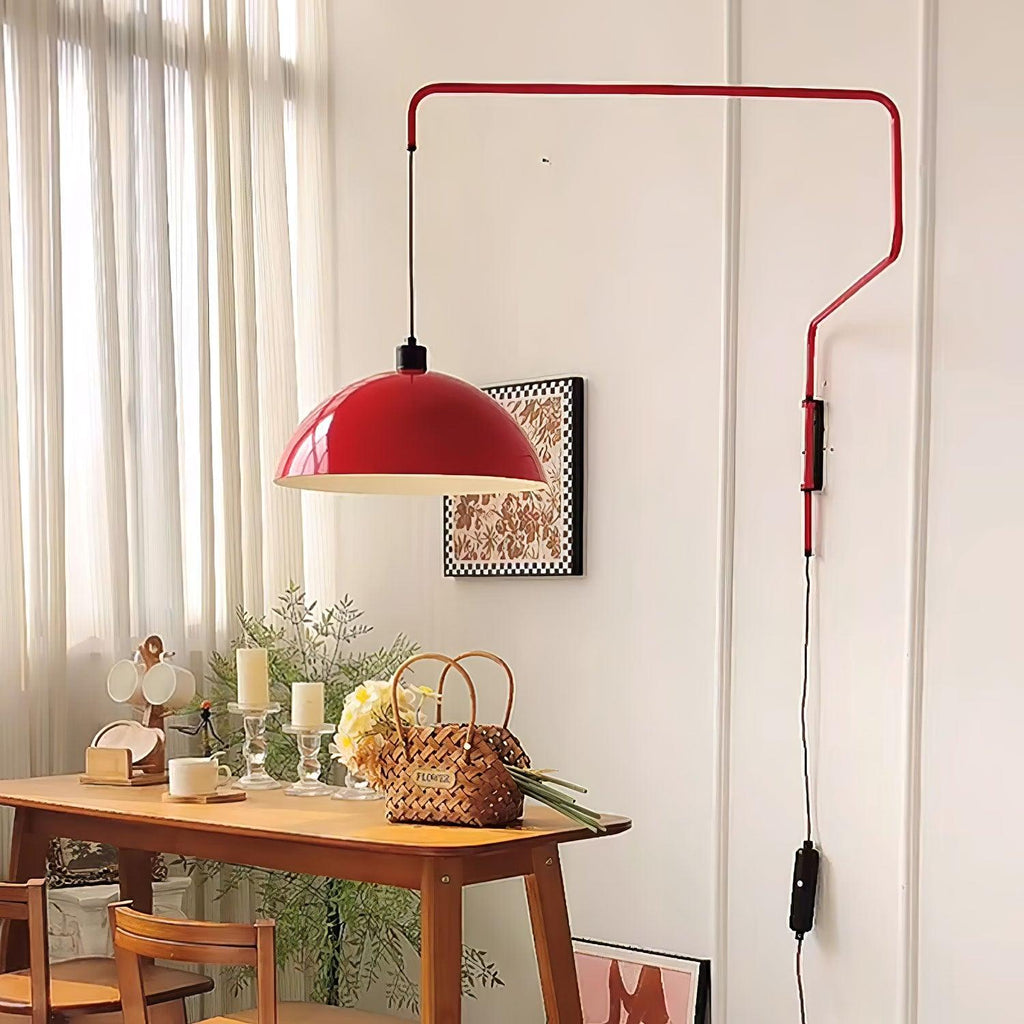 This Clérachic wall light in red hangs beside tall sheer curtains, over a wooden console table with candles and a woven basket.