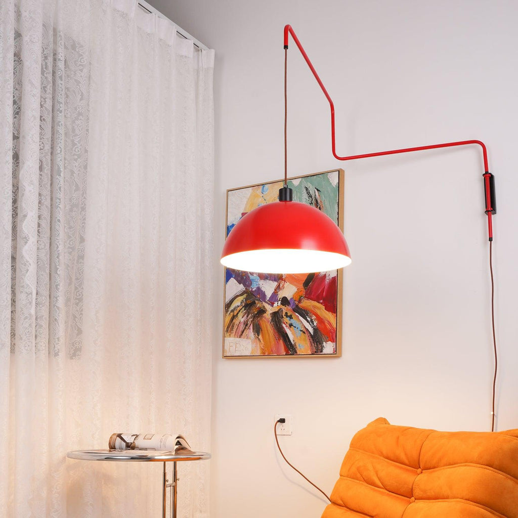 Lit red shade glowing above an orange sofa, with a bold abstract painting behind, shown on this Clérachic wall light.