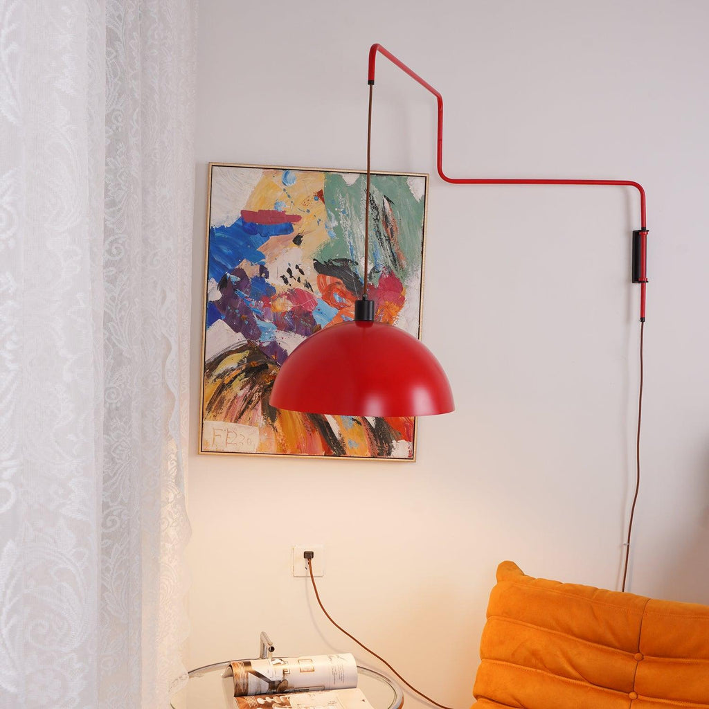 This Clérachic wall light in red, the shade swung over the abstract painting, with an orange sofa and glass side table below.