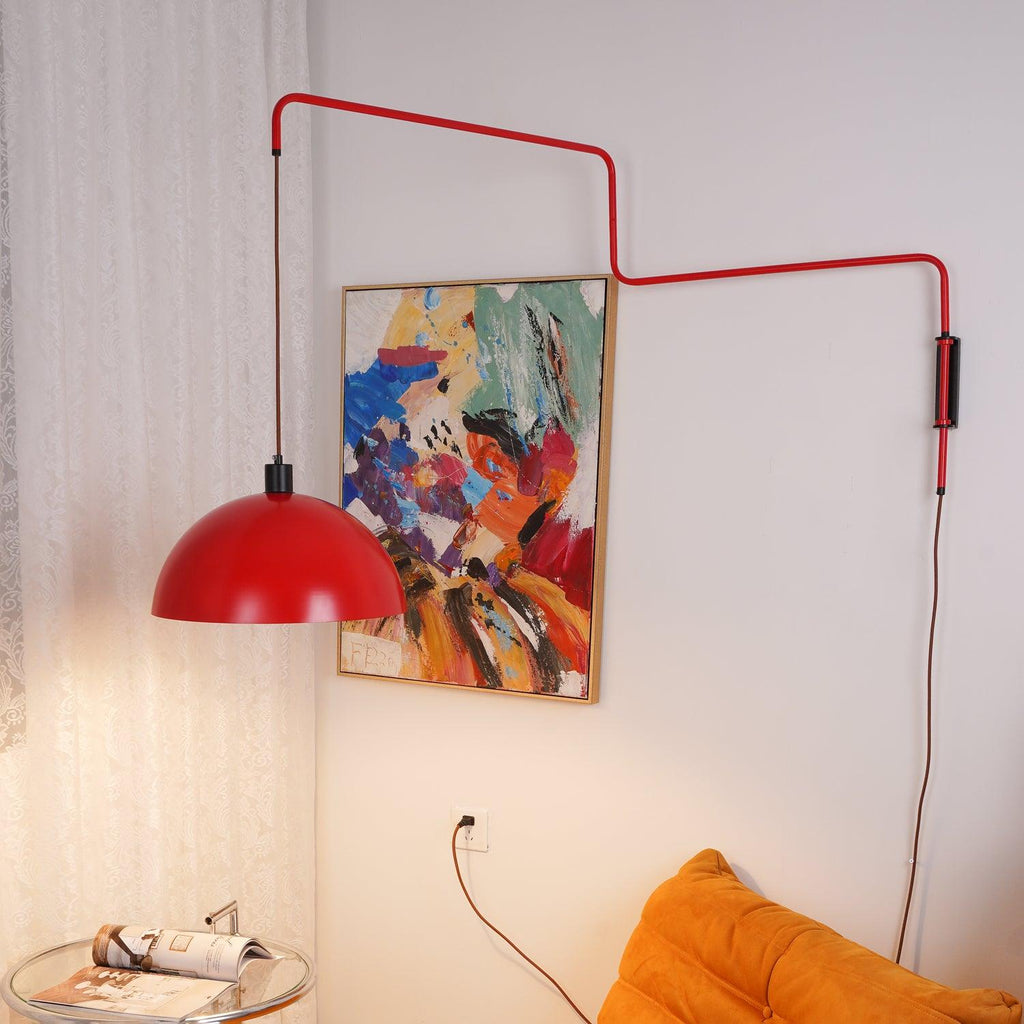 Shade pulled out to the left on this Clérachic wall light, its red arm stretched above a warm-lit orange sofa and painting.