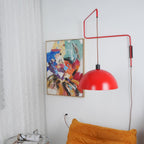 Red shade of this Clérachic wall light swung to the right of an abstract painting, the zigzag arm clear against a white wall.