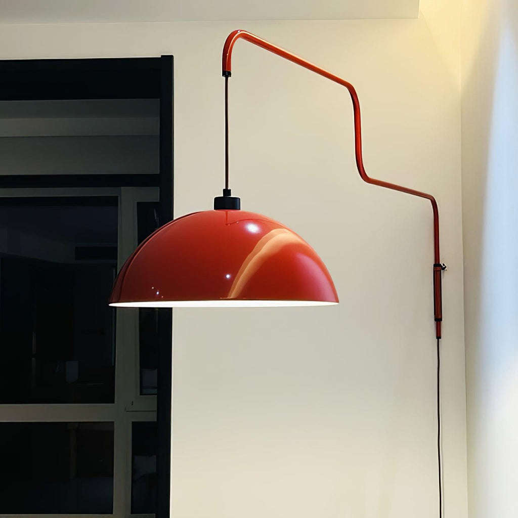 Large red dome of this Clérachic wall light with a glossy highlight, on its zigzag arm against a cream wall.