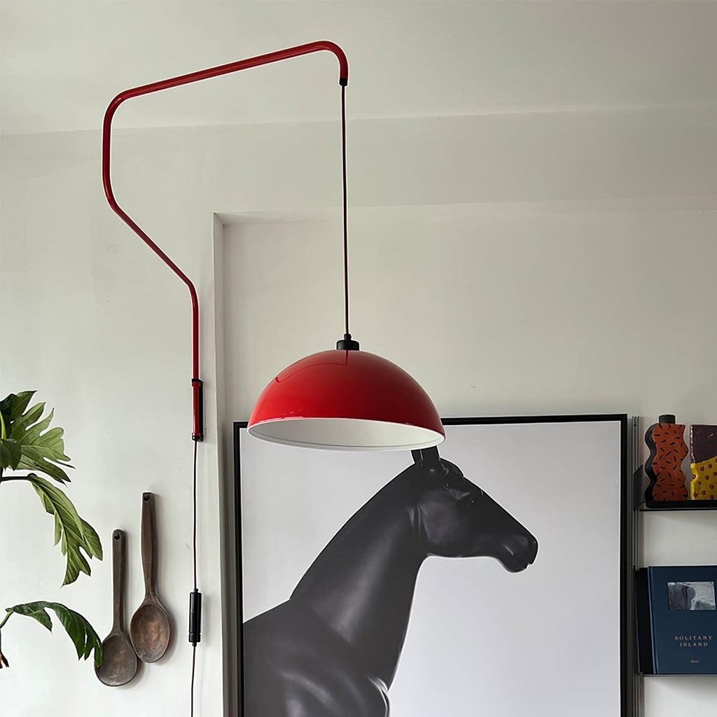 A red Clérachic wall light hangs over a framed horse sculpture print, with wooden spoons and a leafy plant on the wall.