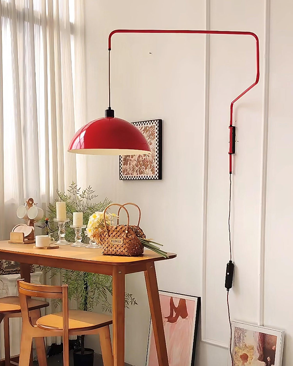 Red shade of this Clérachic wall light above a wooden console table with candles and a flower basket in a bright room.