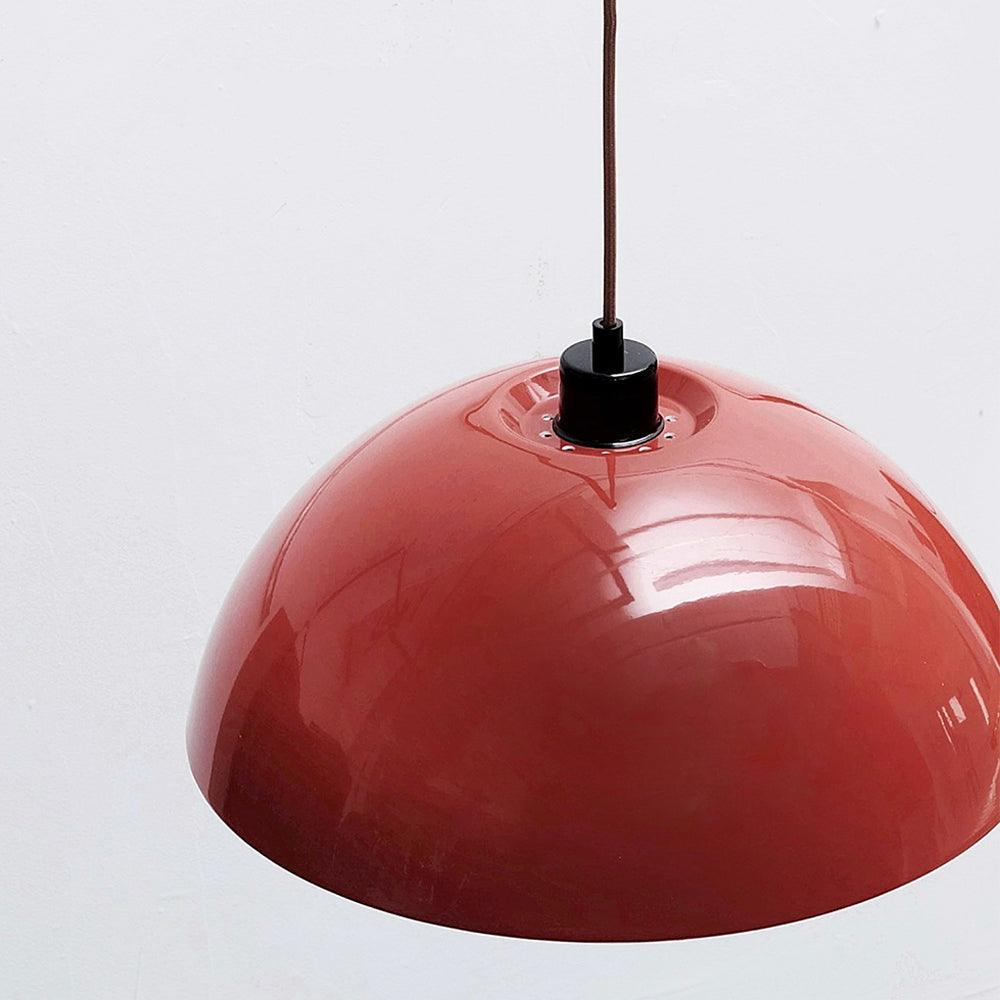 Close view of the glossy red dome and black cord grip on this Clérachic wall light.
