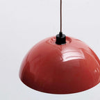 Close view of the glossy red dome and black cord grip on this Clérachic wall light.