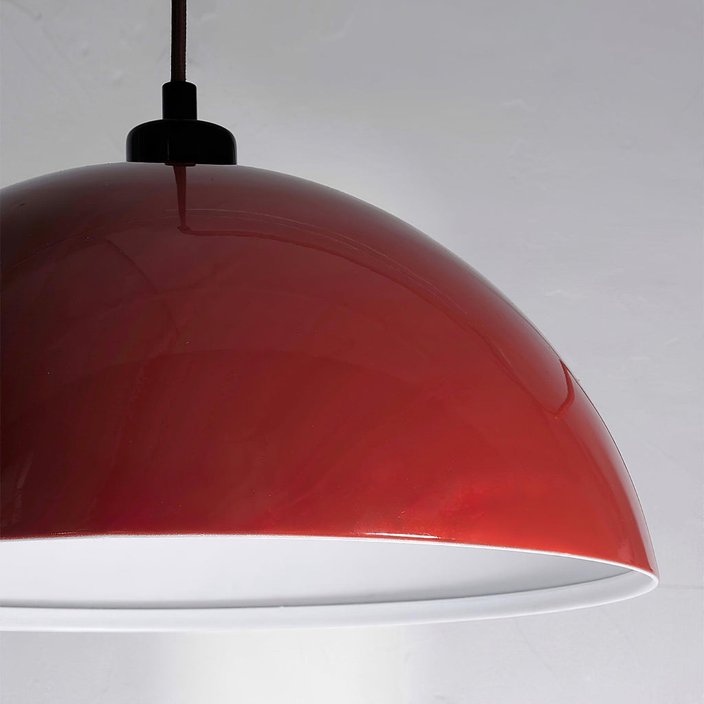 Underside view of this Clérachic wall light's red dome, showing its white interior against a pale grey wall.