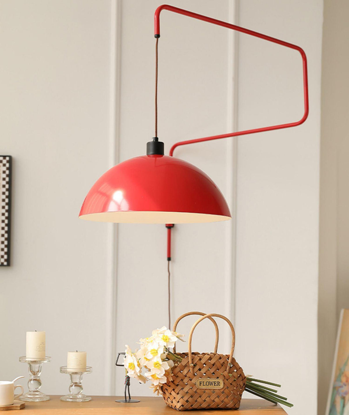Red Clérachic wall light with a wide zigzag arm, over a wooden console with candles and a woven basket of flowers.