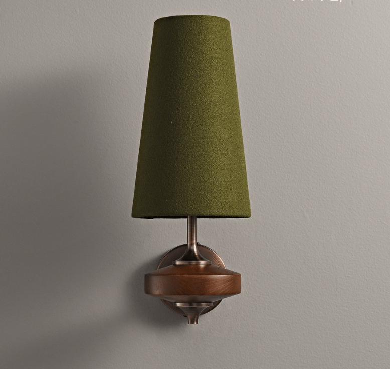 A green fabric shade tops this Clérachic single wall sconce, set against a grey wall above a walnut disc.