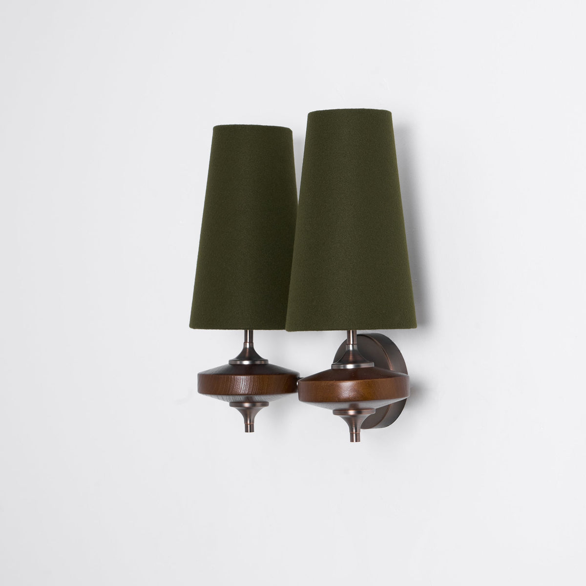 Side-on view of a Clérachic two-light wall sconce with green shades overlapping, on a plain pale wall.