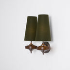 Three-quarter view of a Clérachic twin sconce with green shades, its walnut discs and round bronze plate on white.