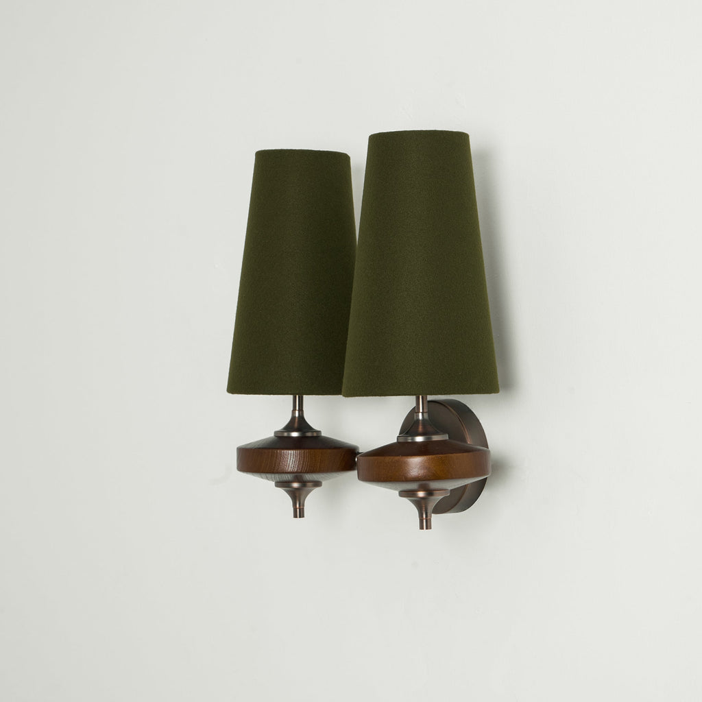 Side view of a Clérachic twin wall sconce with two green shades, one arm angled out from a bronze backplate.