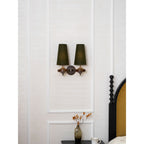 Unlit green shades on a Clérachic twin wall light, hung on a white panelled wall over a bedside vase and mug.