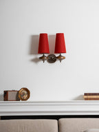 A small Clérachic twin sconce with red shades above a white mantel, a vintage radio and a taupe sofa.