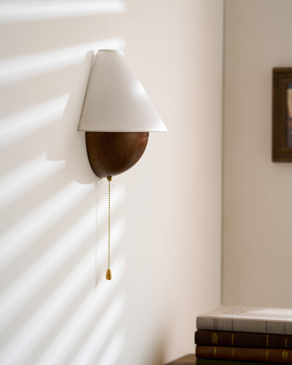 Side-on view of this Clérachic wall light, showing the shade and the half-sphere base standing out from a sunlit wall.