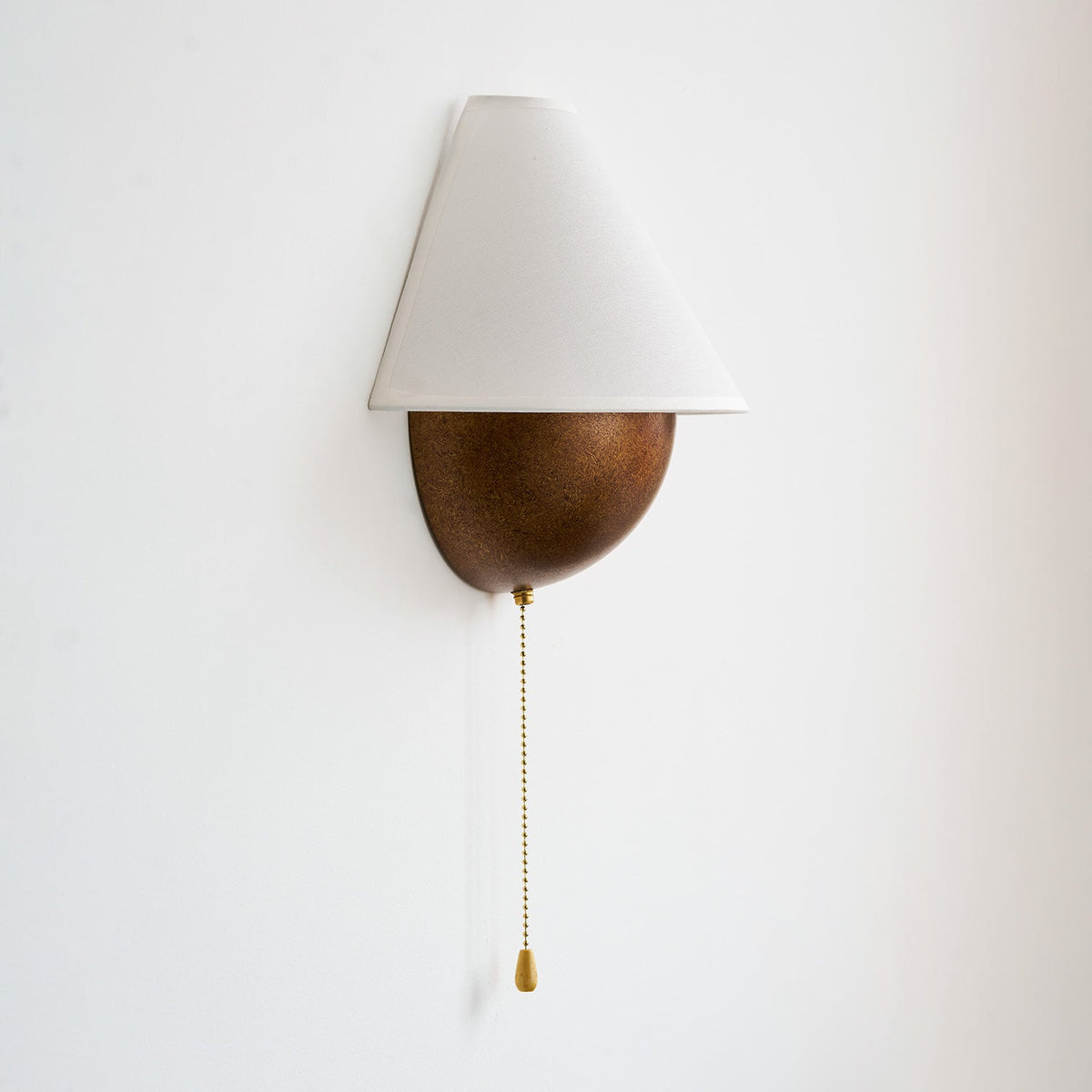 Clérachic wall light on a white wall, angled slightly to show the tapered shade and the curved side of the base.