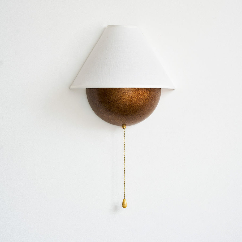 Unlit Clérachic wall light with a white fabric shade and a speckled bronze half-sphere, on a plain white wall.