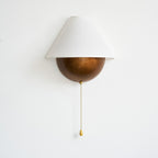 Unlit Clérachic wall light with a white fabric shade and a speckled bronze half-sphere, on a plain white wall.