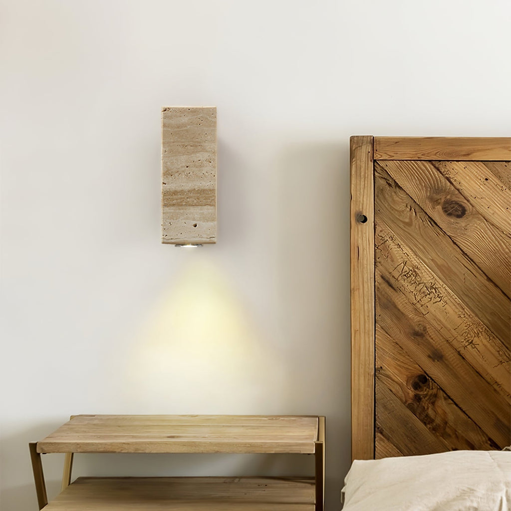 Rectangular stone wall light from Clérachic above a wooden bench, with a knotty plank headboard at the right.