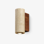 Cylindrical travertine wall light from Clérachic with a walnut-colour backplate, seen at an angle on a white backdrop.