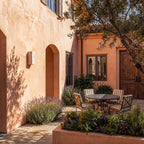 Clérachic unlit rectangular travertine wall light on a sunlit terracotta courtyard wall, its pale stone against the plaster.