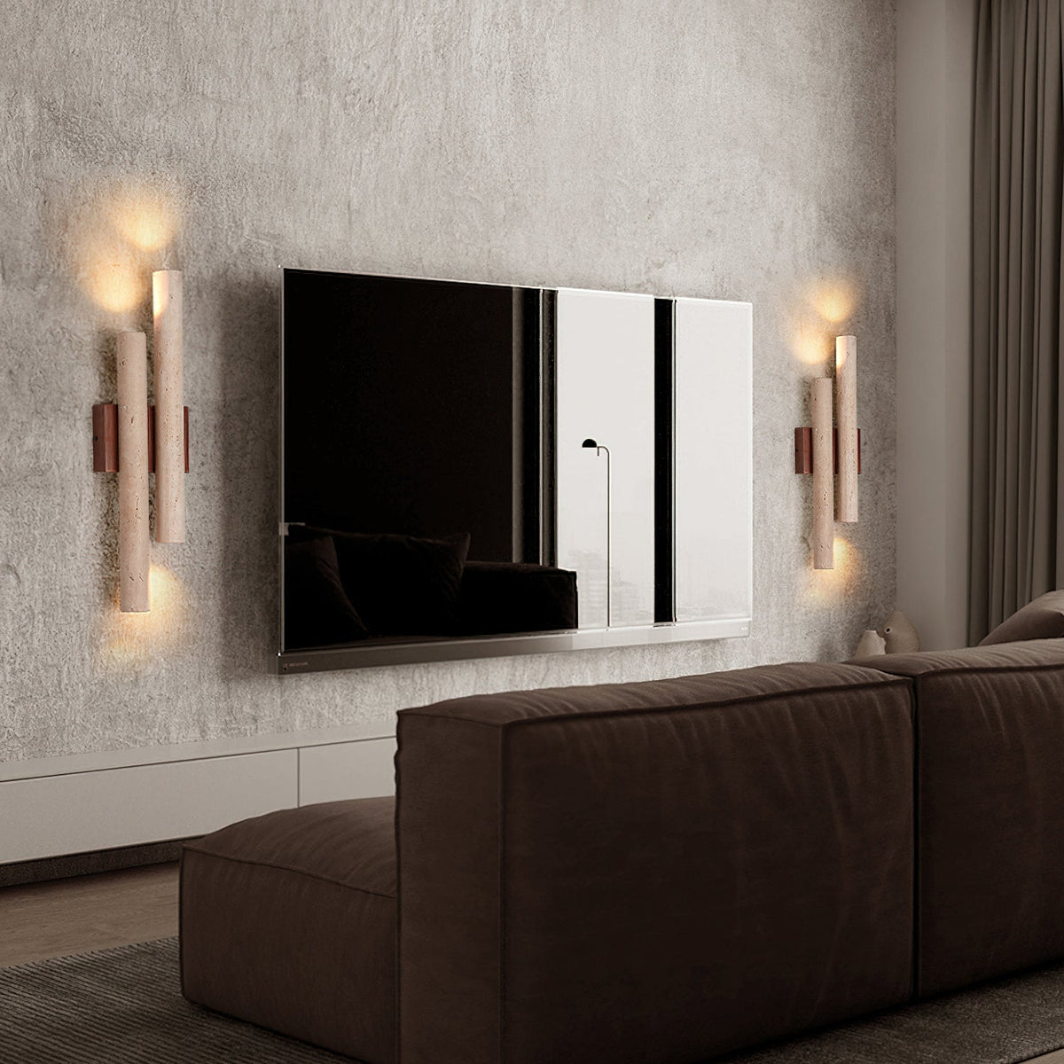 A pair of Clérachic wall lights frames a wall-mounted television above a dark brown sofa, on a rough grey plaster wall.